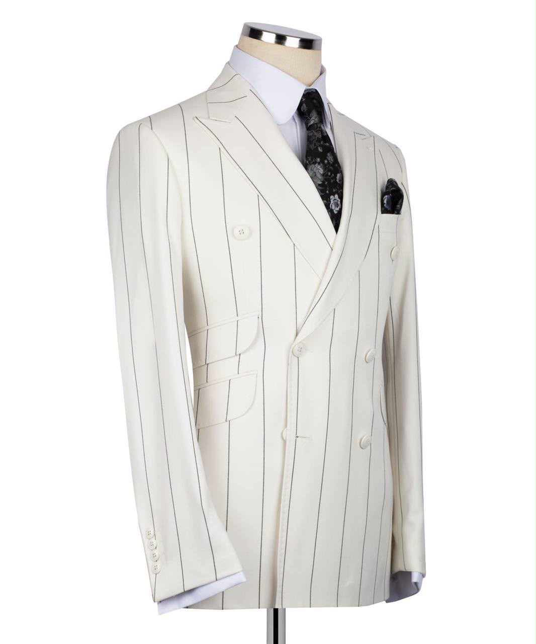 A cream-colored double-breasted pinstripe suit jacket displayed on a mannequin torso, styled with a white dress shirt, a black patterned tie, and a matching pocket square
