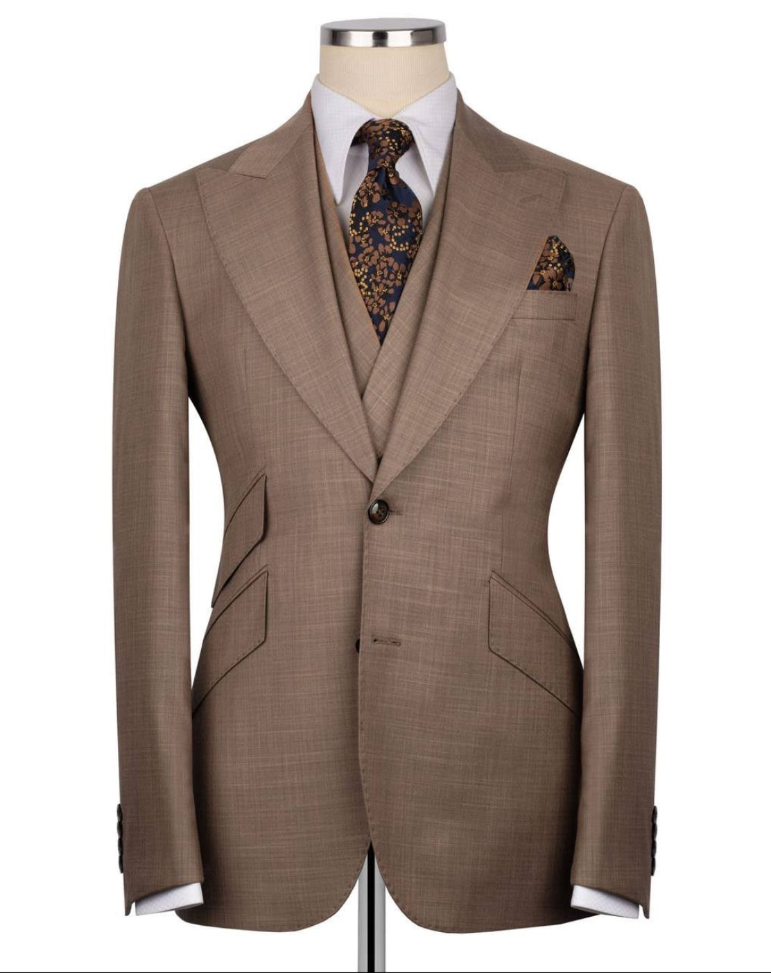 Brown suit jacket on a mannequin with a white shirt, patterned tie, and pocket square.