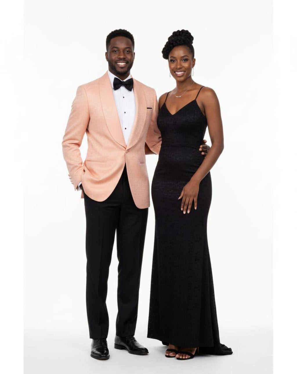 Man in peach tuxedo and woman in black evening gown standing side by side on a white background