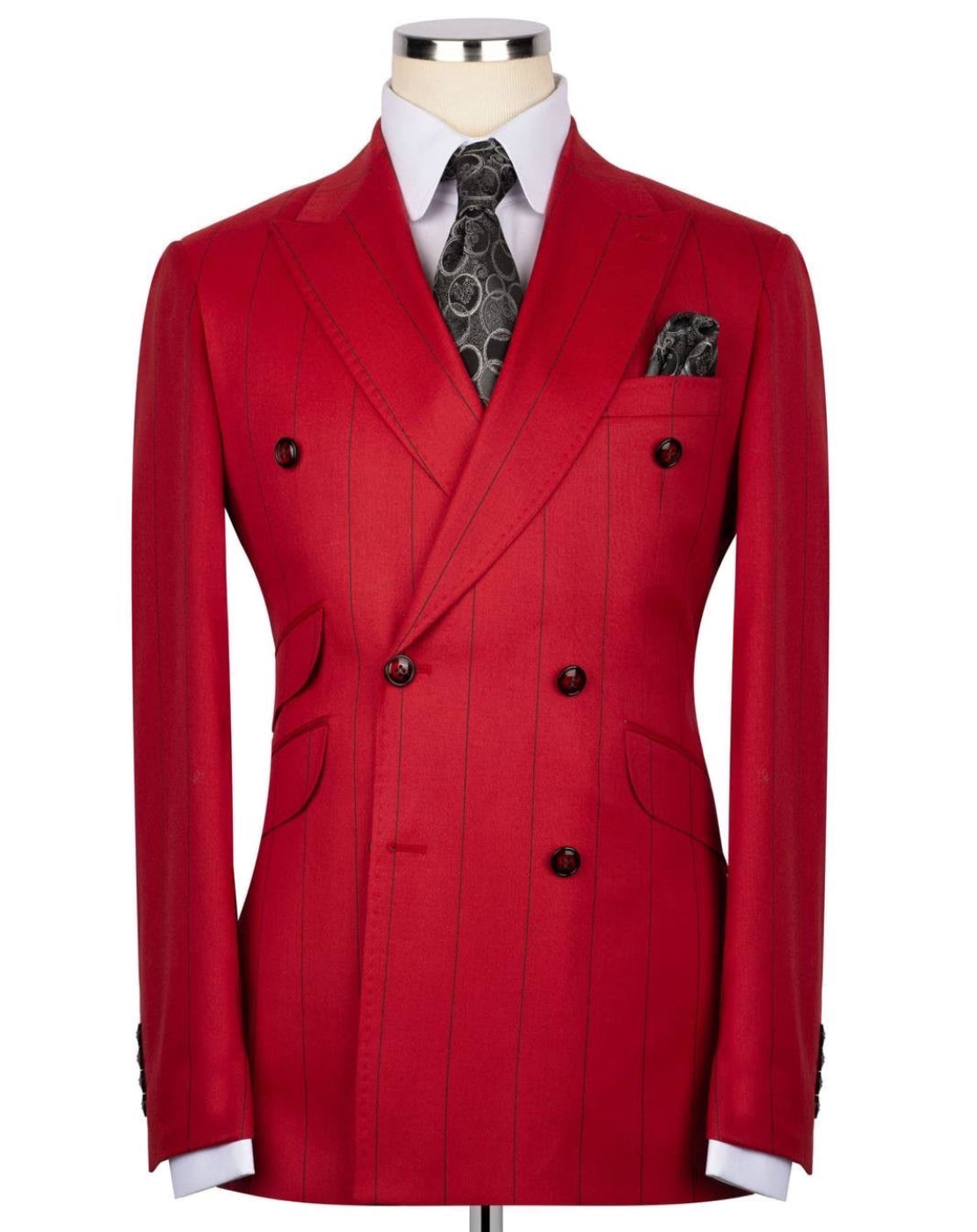 A red double-breasted pinstripe blazer displayed on a mannequin torso, styled with a white dress shirt, a dark patterned tie, and a matching pocket square 