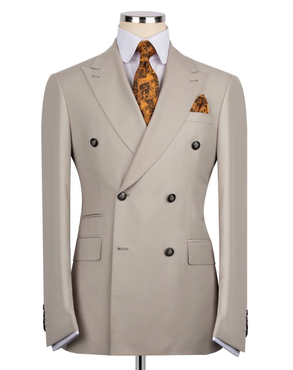 A light beige double-breasted suit jacket displayed on a mannequin torso, styled with a white dress shirt, an orange and black patterned tie, and a matching pocket square against a plain white background.