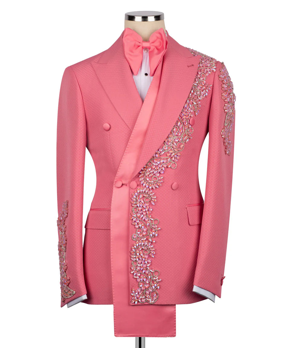 Men's luxury vibrant pink double-breasted tuxedo jacket featuring an innovative asymmetrical extended satin sash, matching oversized bow tie, and heavy pink crystal floral appliqués on the lapel, shoulder, and cuffs