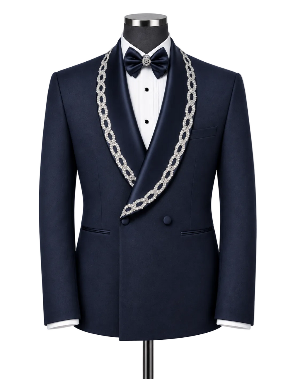 A navy blue satin tuxedo jacket displayed on a mannequin with a white dress shirt, a navy bow tie, and a prominent silver chain lapel. The jacket features a double-breasted design with a single front button and a decorative silver chain draped over the shoulders.
