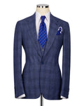 A blue windowpane plaid suit jacket displayed on a mannequin torso, styled with a white dress shirt, a blue patterned tie, and a matching pocket square.