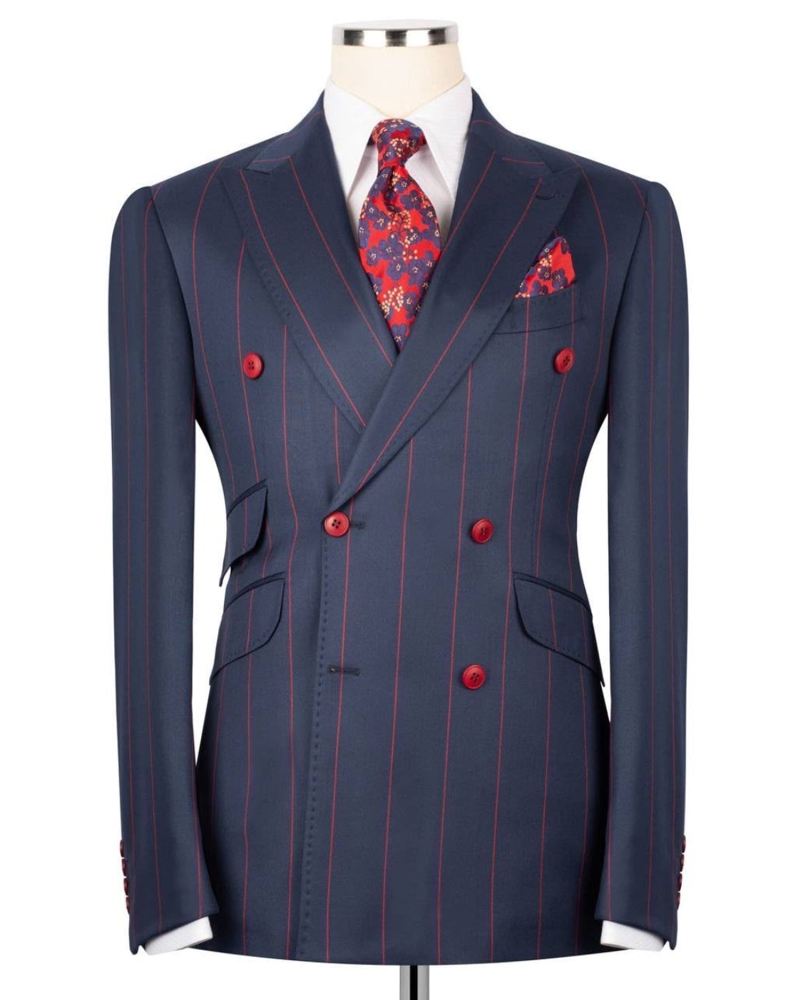 A navy blue double-breasted suit jacket with thin red pinstripes, styled on a mannequin with a white dress shirt, a red patterned tie, and a matching pocket square.