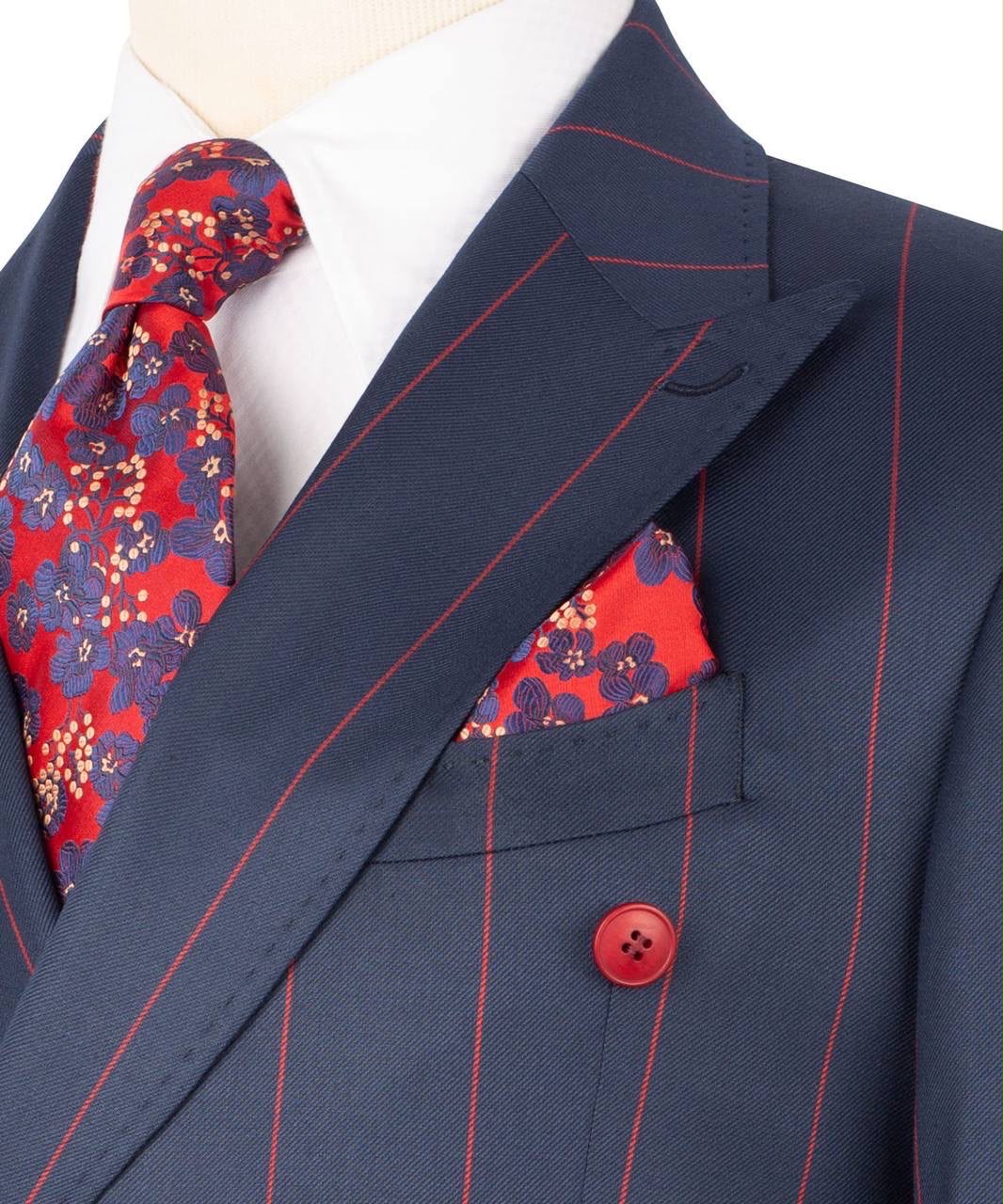 A close-up of a navy blue double-breasted suit jacket with thin red pinstripes, styled with a white dress shirt, a red and navy floral tie, and a matching red and navy floral pocket square.
