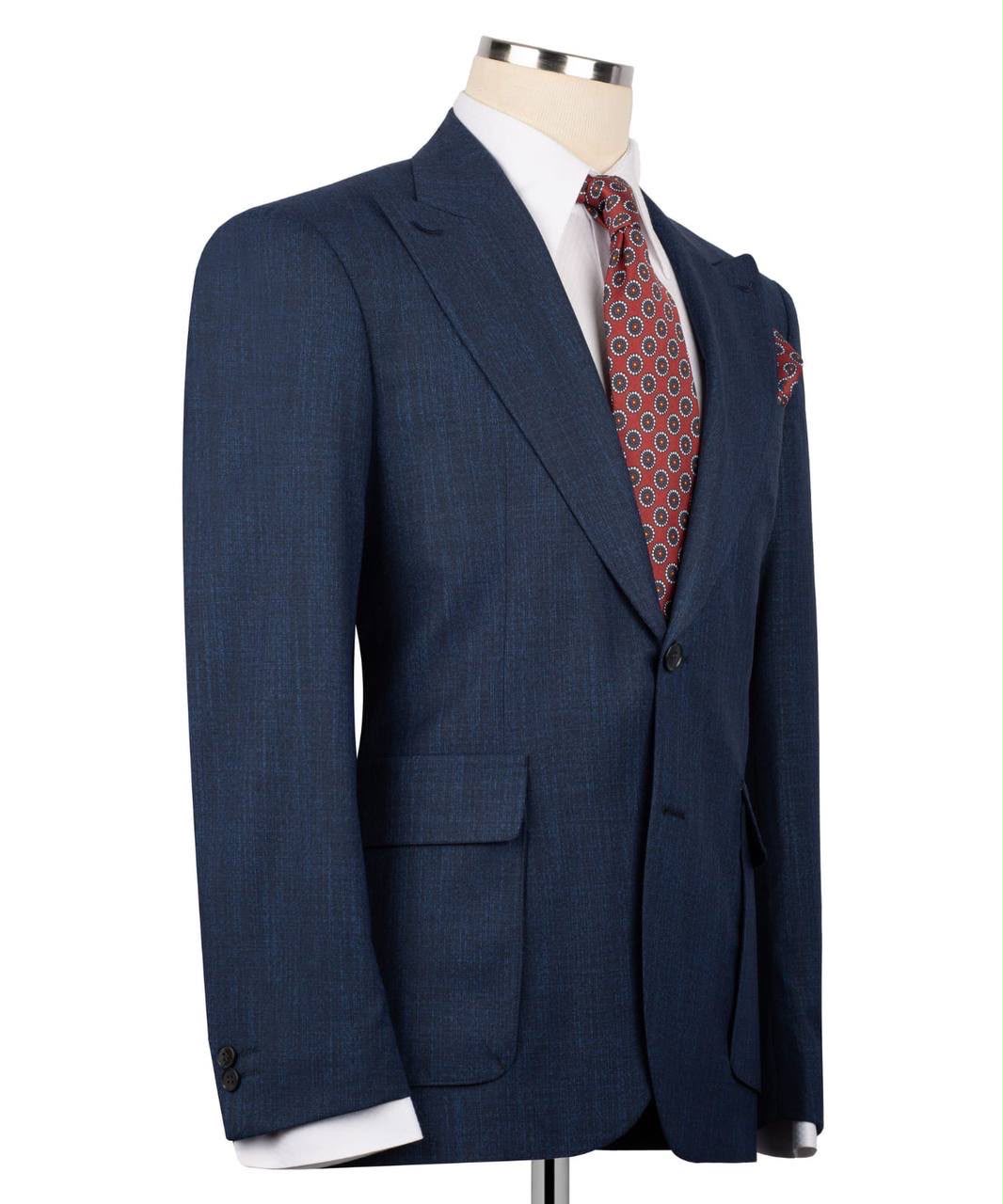 A navy blue textured suit jacket displayed on a mannequin torso, styled with a white dress shirt and a red patterned tie.