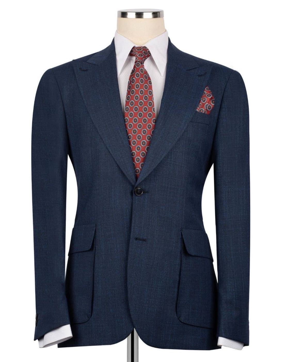 A navy blue textured suit jacket displayed on a mannequin torso, styled with a white dress shirt, a red and gold patterned tie, and a matching pocket square.
