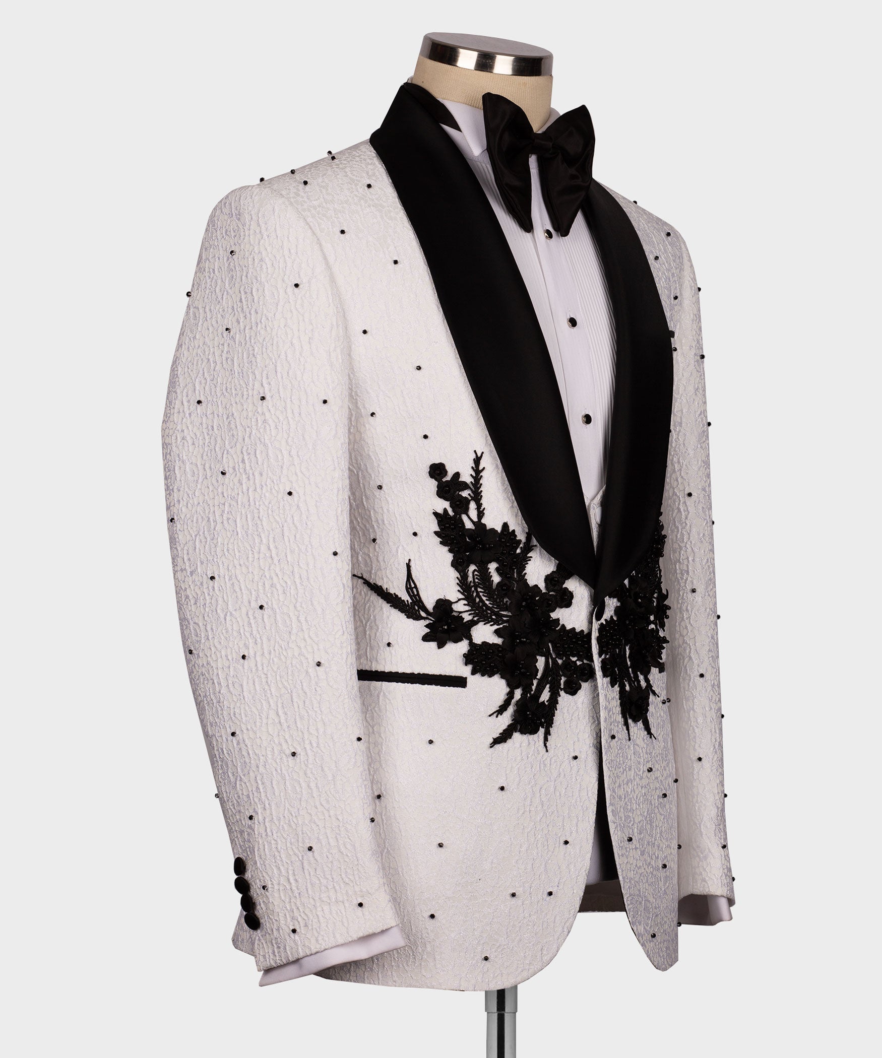 White tuxedo jacket side view with black lapels and large floral appliqué detail