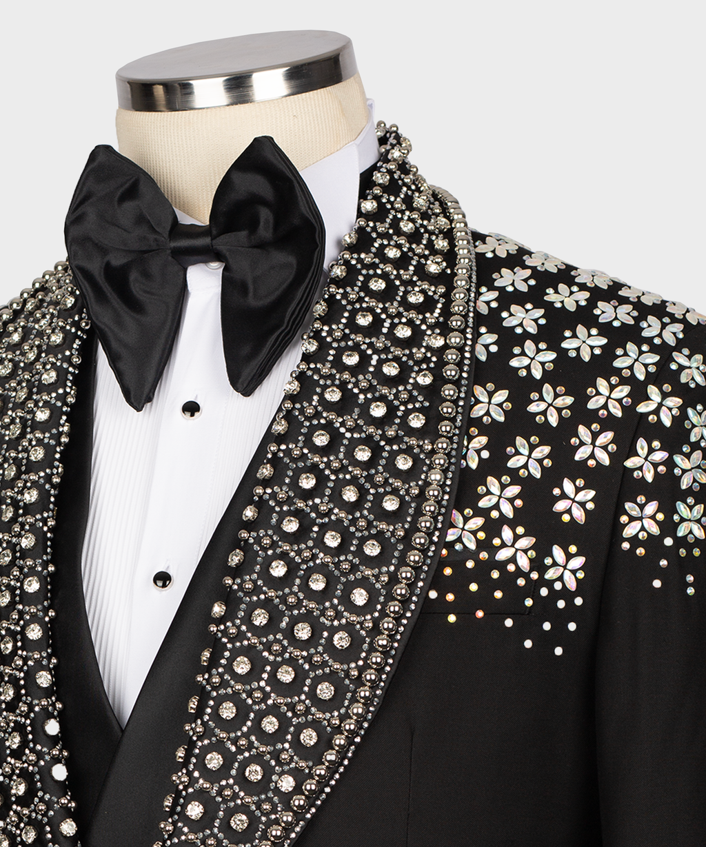 Close-up: black tuxedo bow tie, studded white shirt front, and stone-embroidered lapel trim