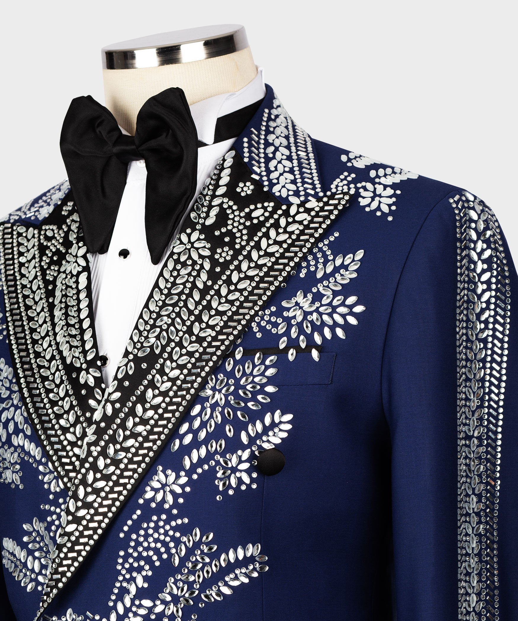 Close-up of dark blue tuxedo jacket with silver stone embroidery, black satin lapel, two-button front