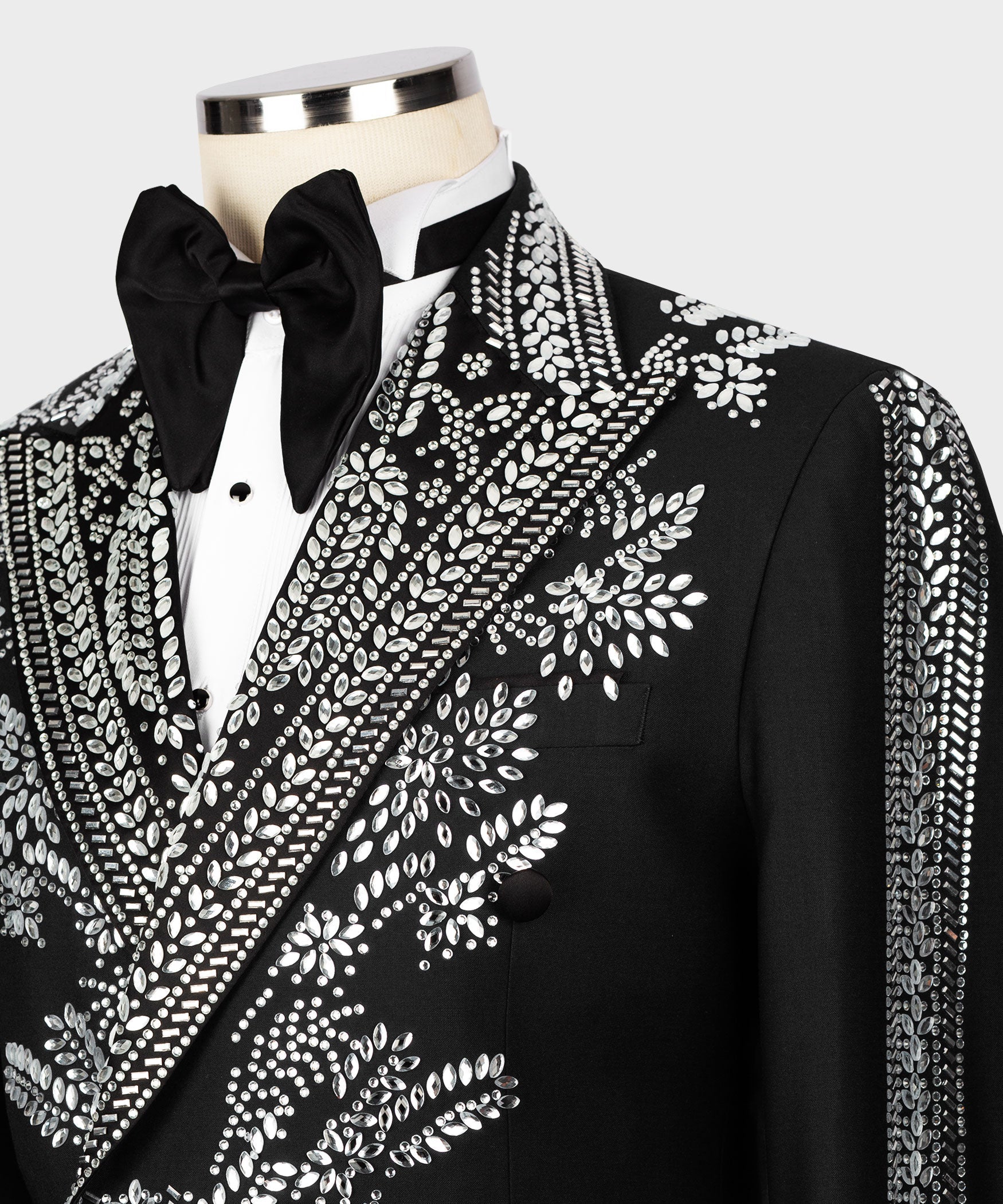 Close-up: black tuxedo lapel with dense silver stone-like embroidery and satin bow tie