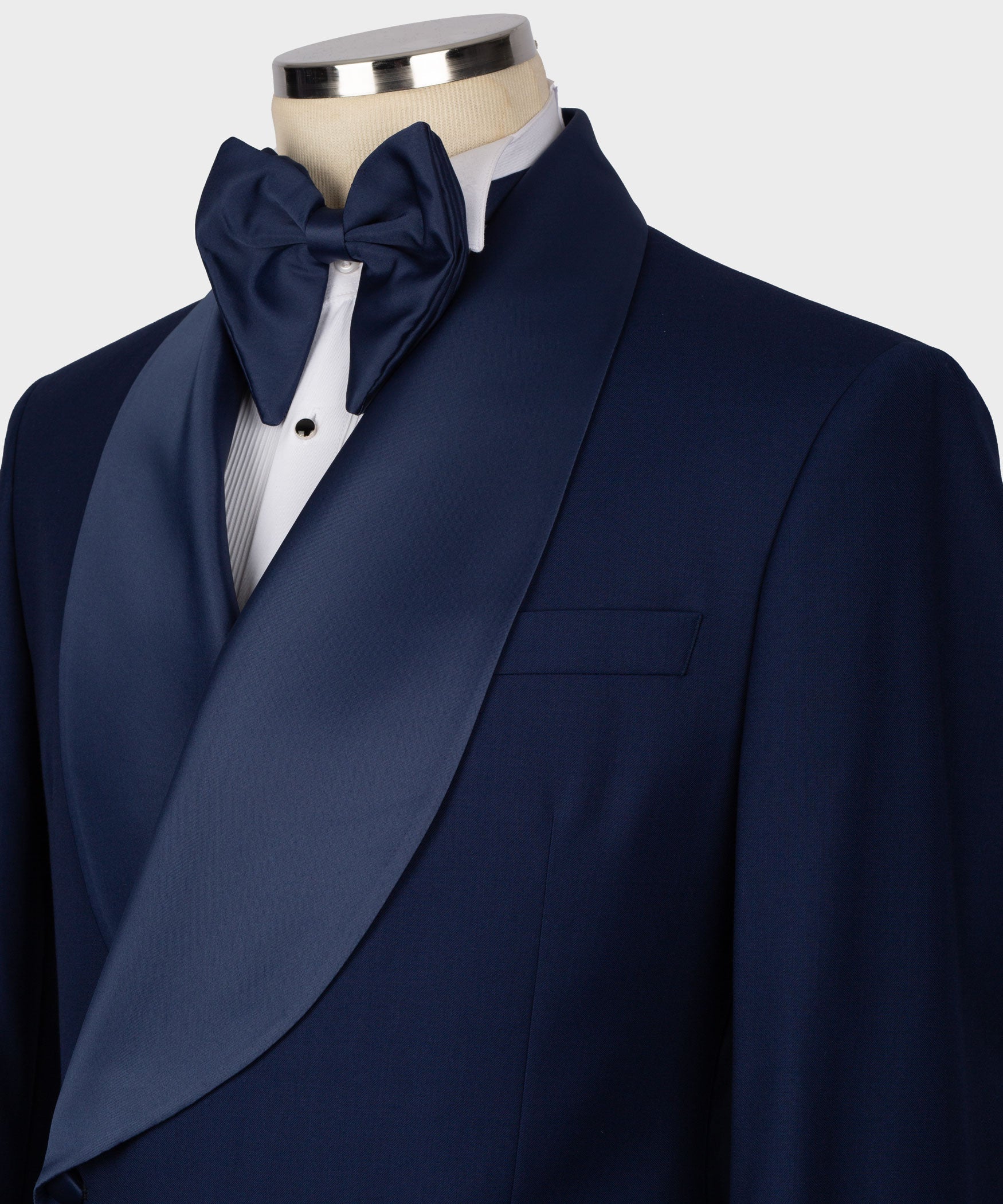 Navy tuxedo lapel with large satin bow tie over white dress shirt, vest