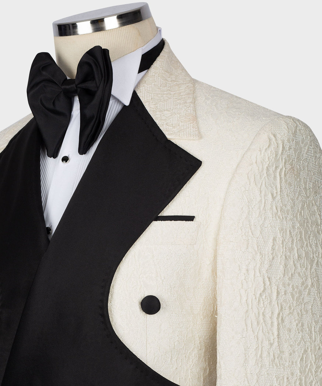 Close-up: black bow tie, white shirt front, black vest, and cream textured lapel