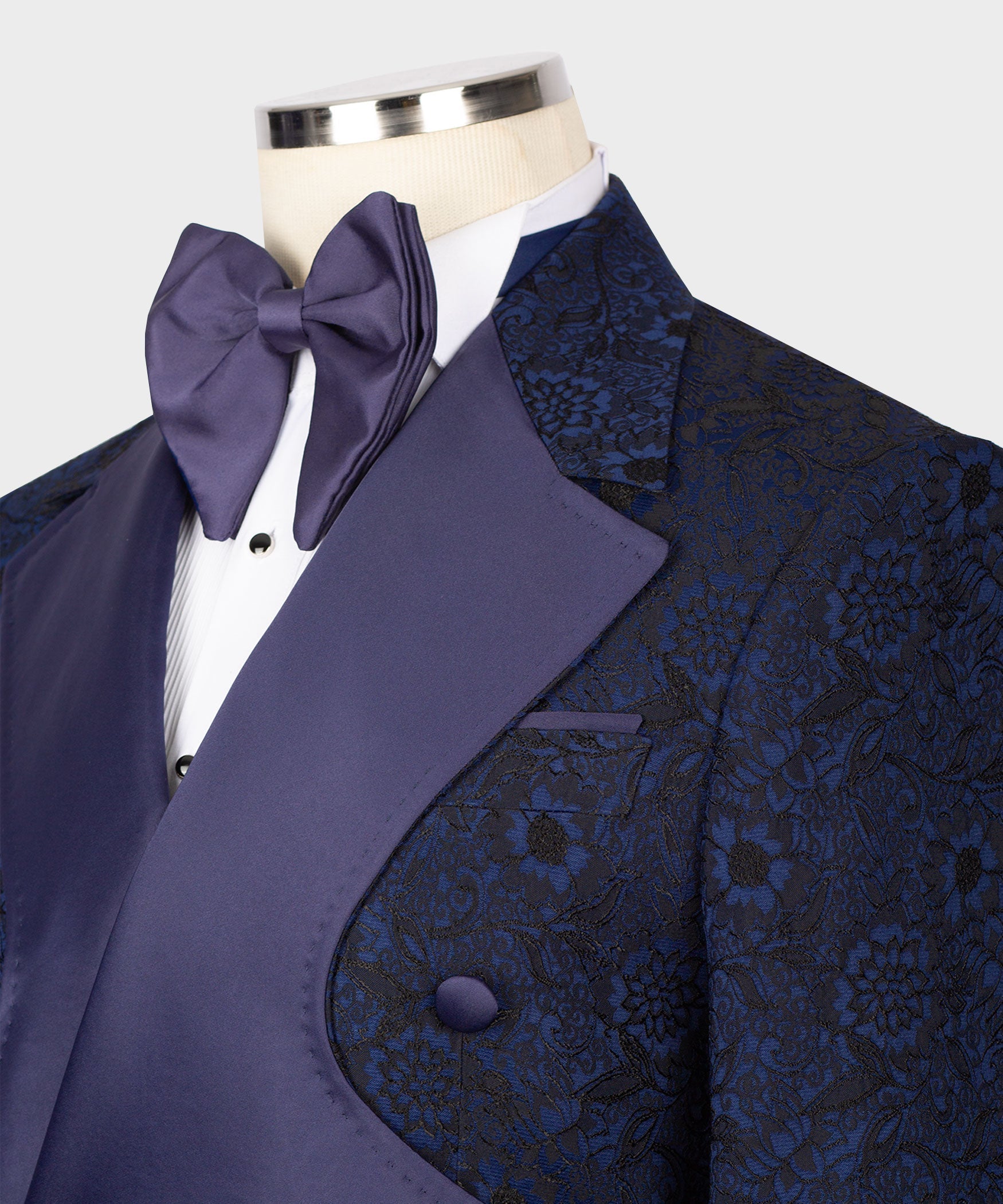 Navy tuxedo jacket close-up with satin bow tie, peaked lapels and floral texture