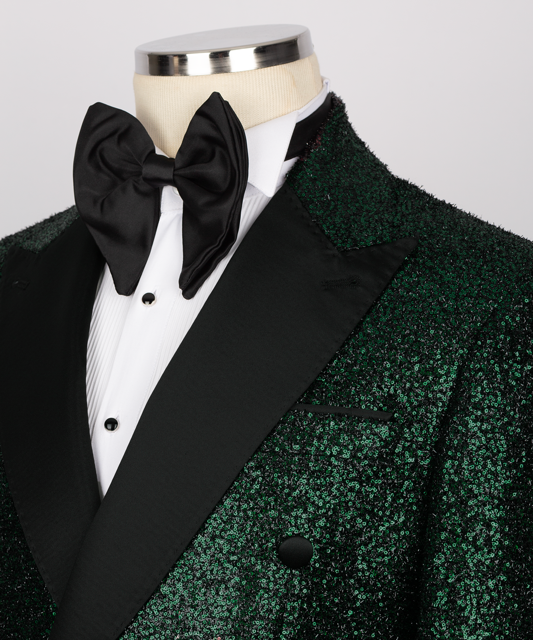 Close-up green sequin tuxedo with black bow tie, satin lapels, velvet trim