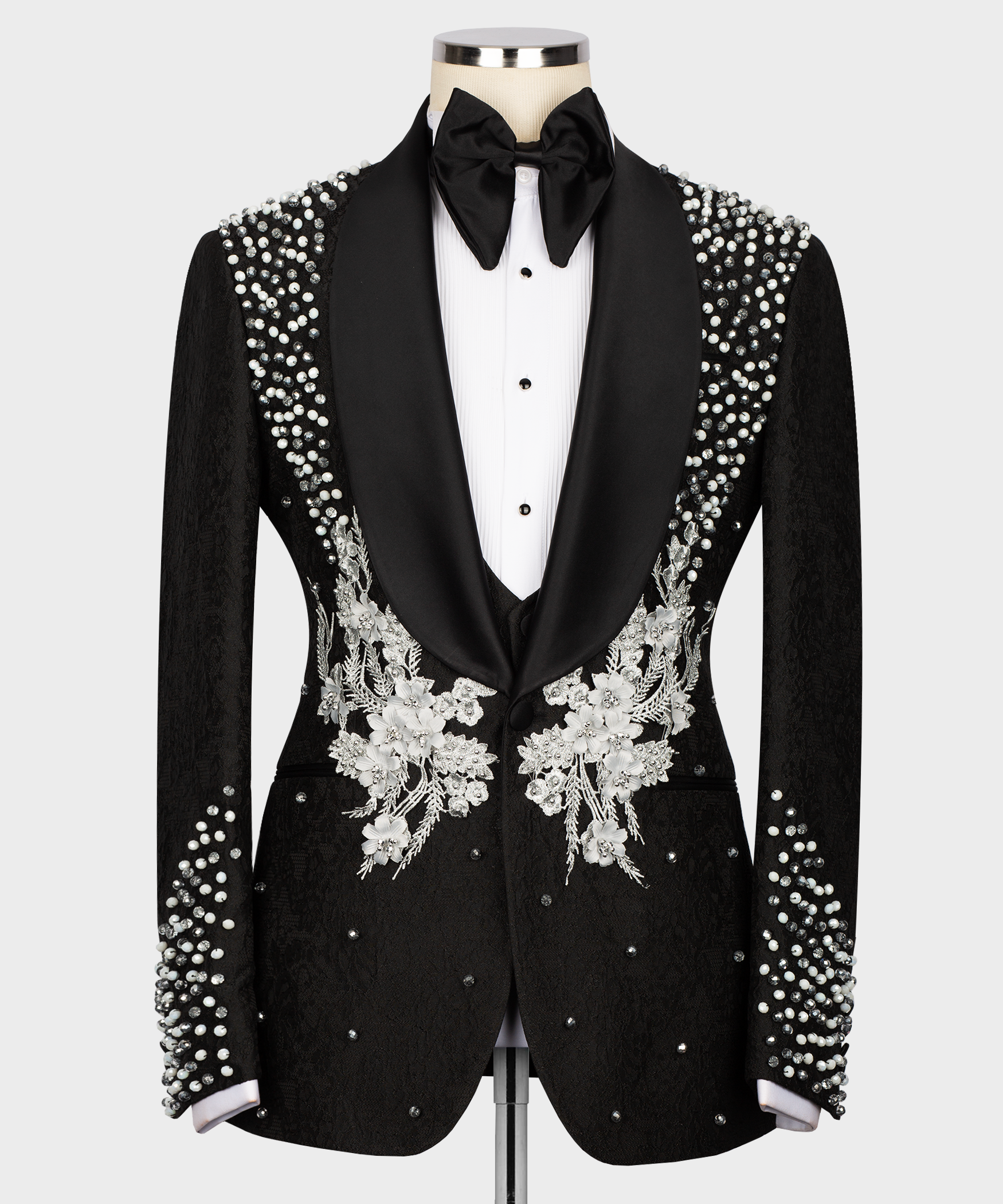 Black tuxedo suit with stone-embroidered lapels and floral vest appliqué, bow tie