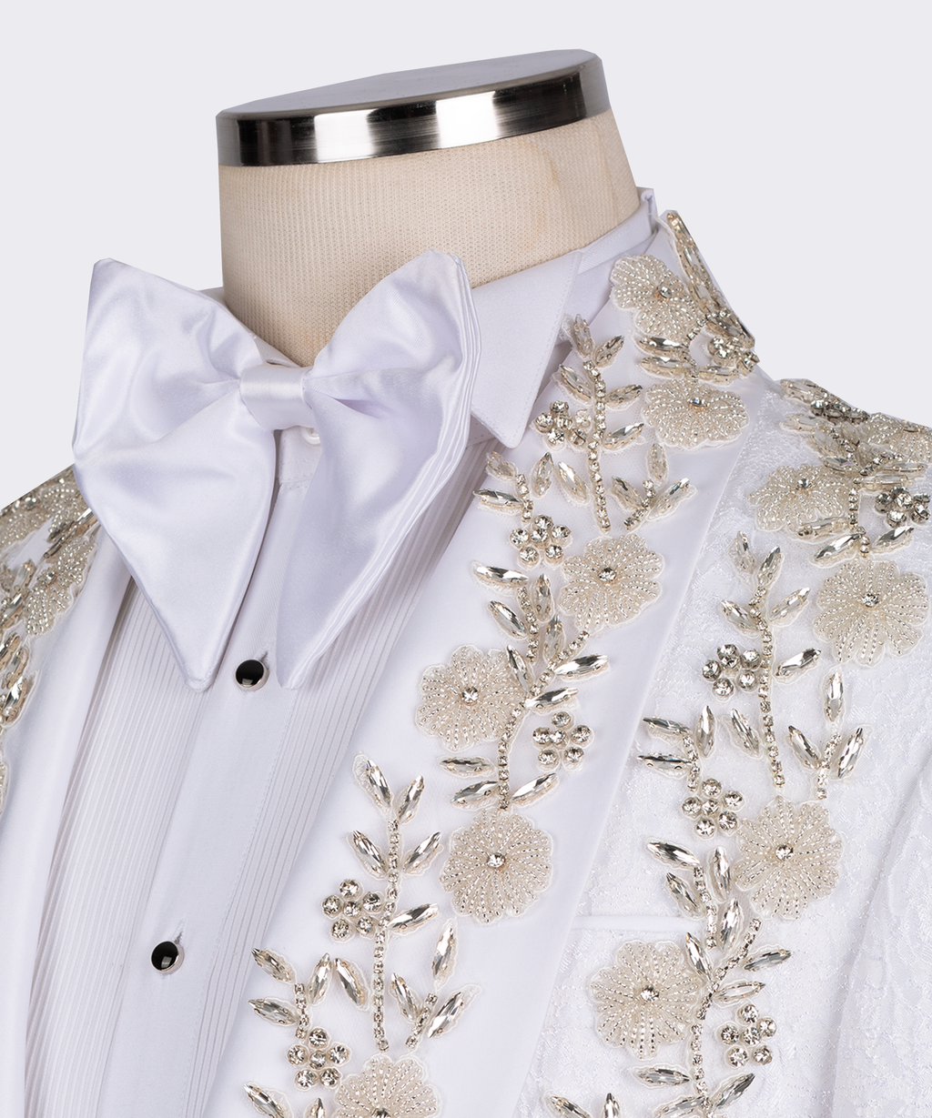 Close-up of white tuxedo shirt and satin bow tie with gold floral and stone embellishment