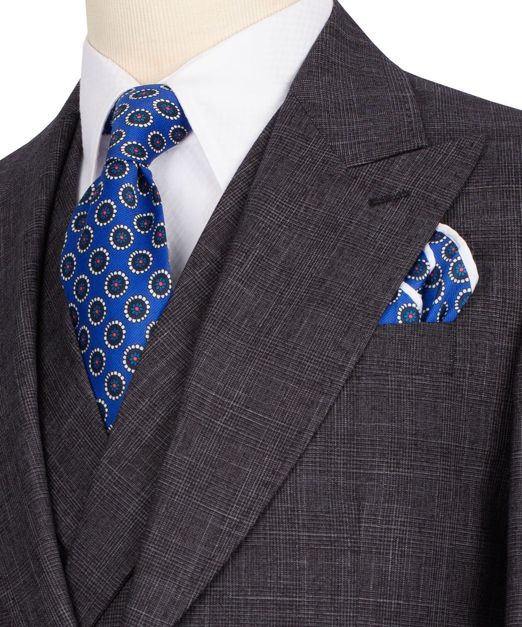 Close-up of dark plaid blazer lapel with blue patterned tie and matching pocket square