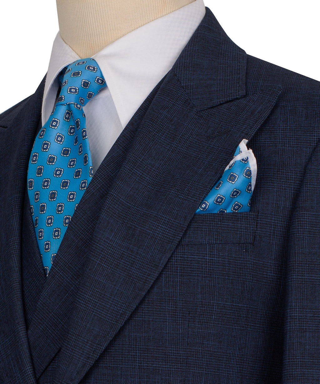 Close-up: dark navy suit lapel with blue patterned tie and matching pocket square