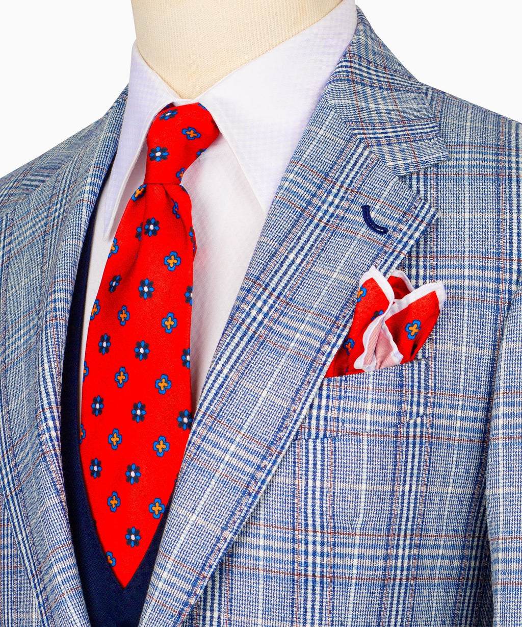 Close-up plaid suit jacket with red patterned tie and folded white pocket square