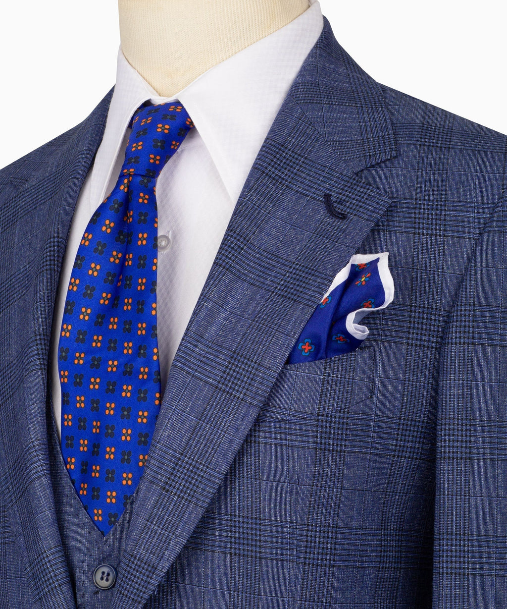 Close-up of blue plaid suit jacket lapel with blue patterned tie and folded pocket square