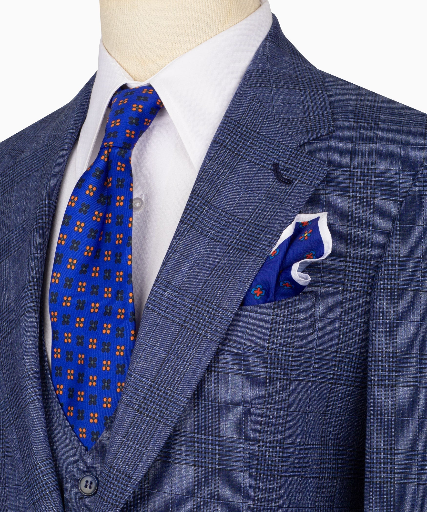Close-up of blue plaid suit jacket lapel with blue patterned tie and folded pocket square