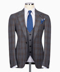 Grey plaid men’s suit jacket with black waistcoat, blue patterned tie and pocket square