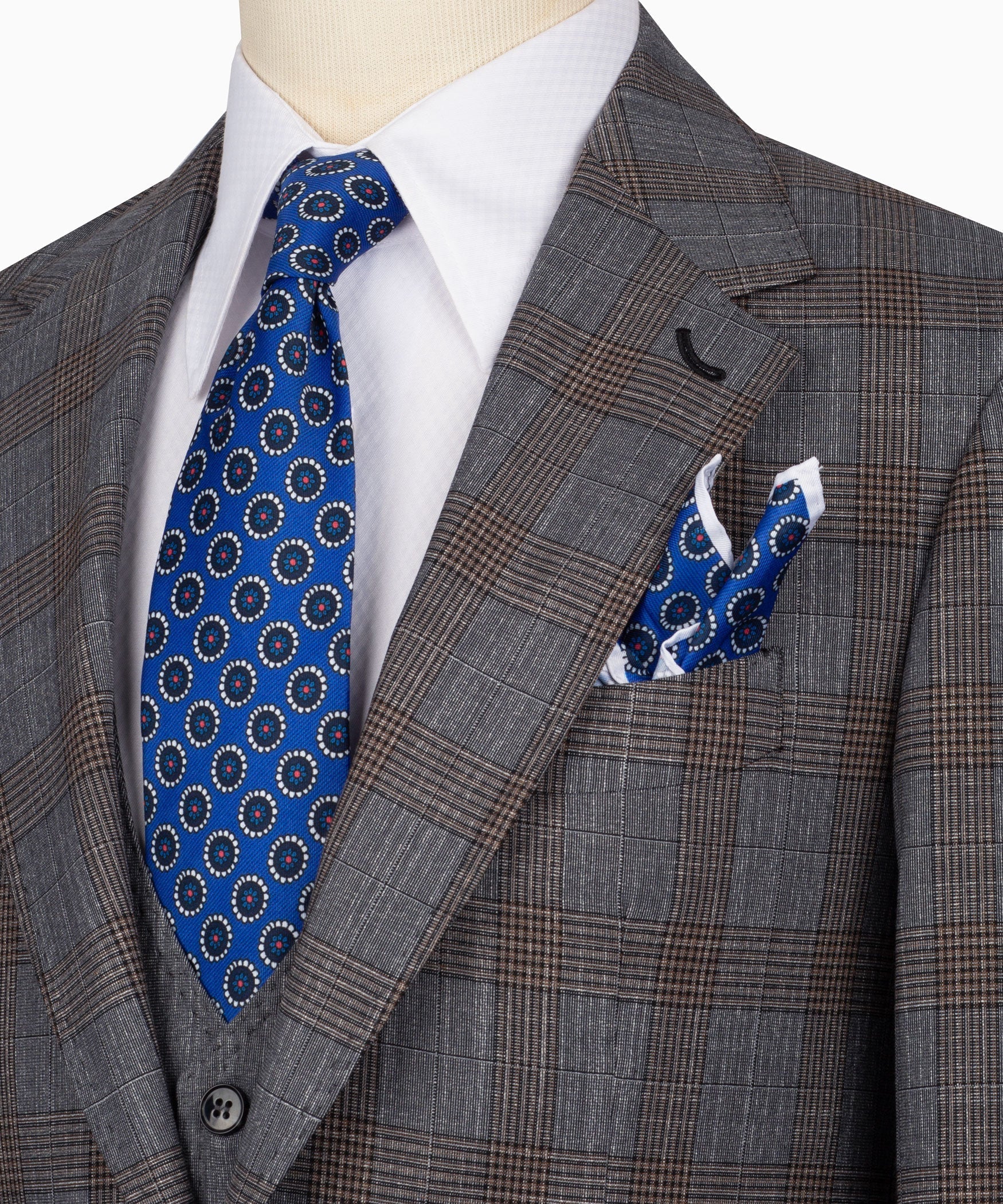 Close-up of grey plaid blazer lapel with blue patterned tie and matching pocket square