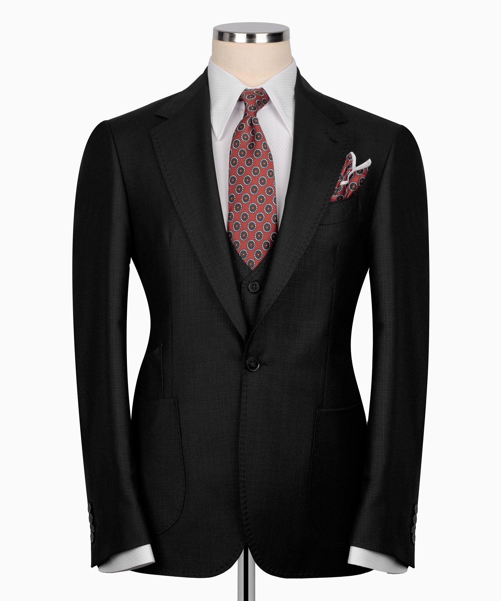 Black suit jacket with center button vest and patterned tie with pocket square.