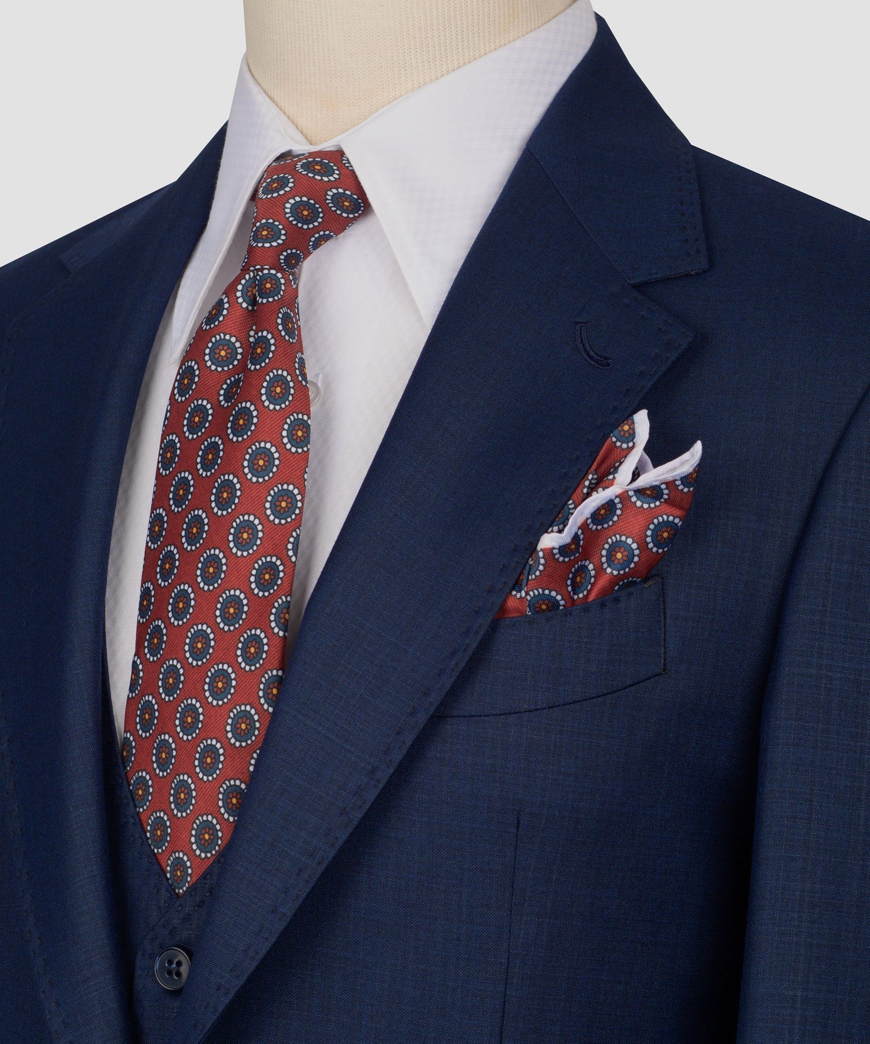 Close-up of navy plaid suit jacket lapel with patterned tie and matching pocket square