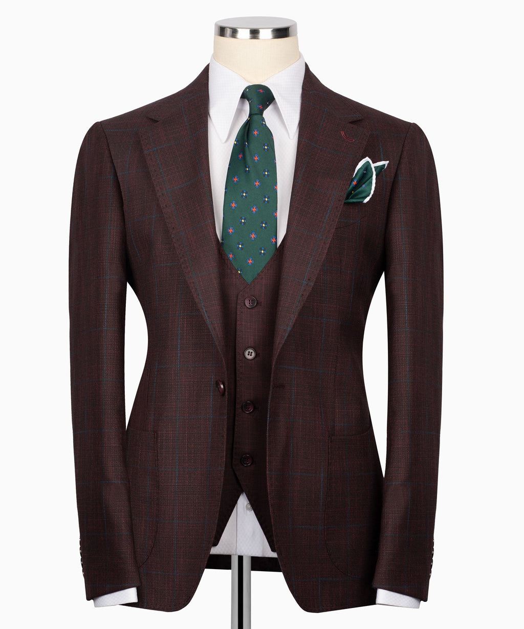 Men’s three-piece plaid suit jacket with green patterned tie and matching pocket square
