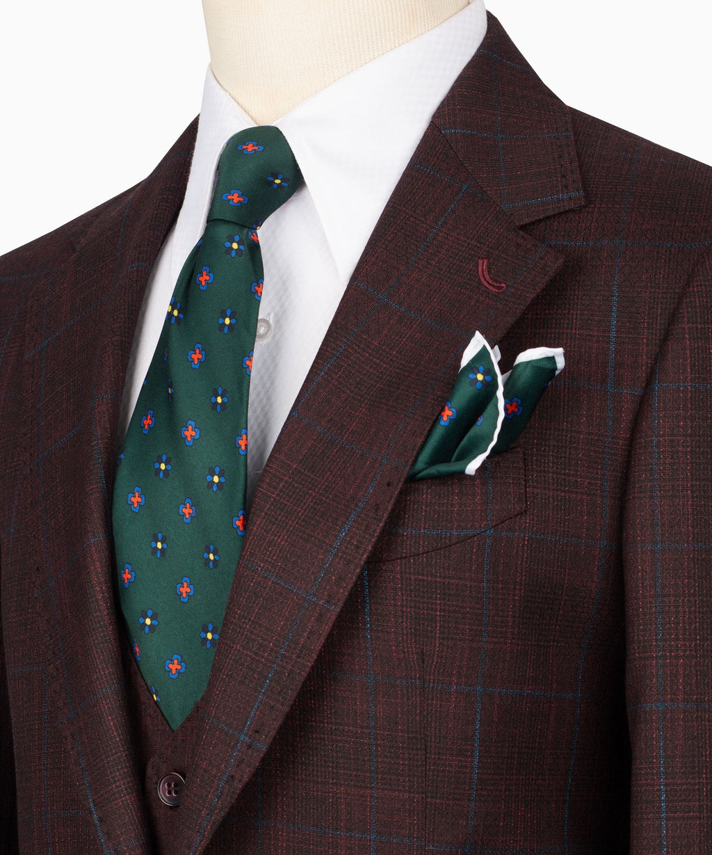 Close-up of plaid suit lapels with white shirt, green patterned tie, and pocket square
