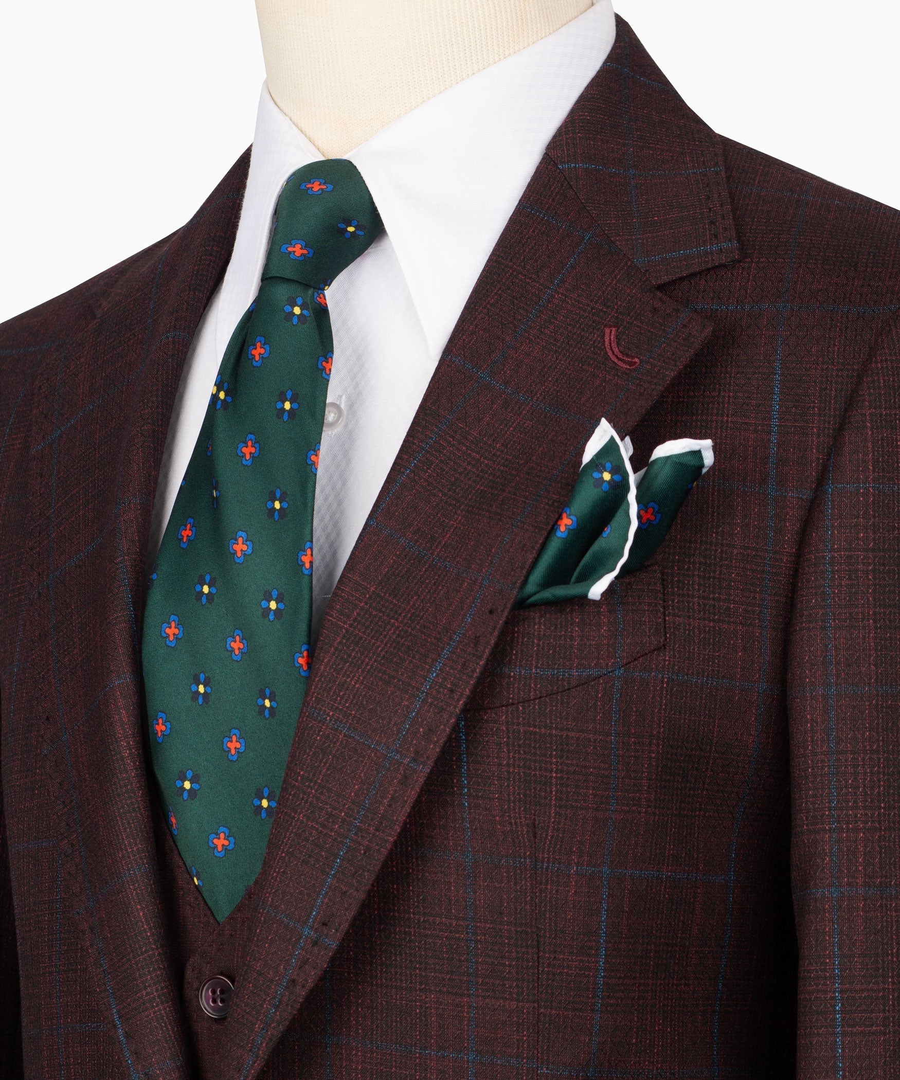 Close-up of plaid suit lapels with white shirt, green patterned tie, and pocket square