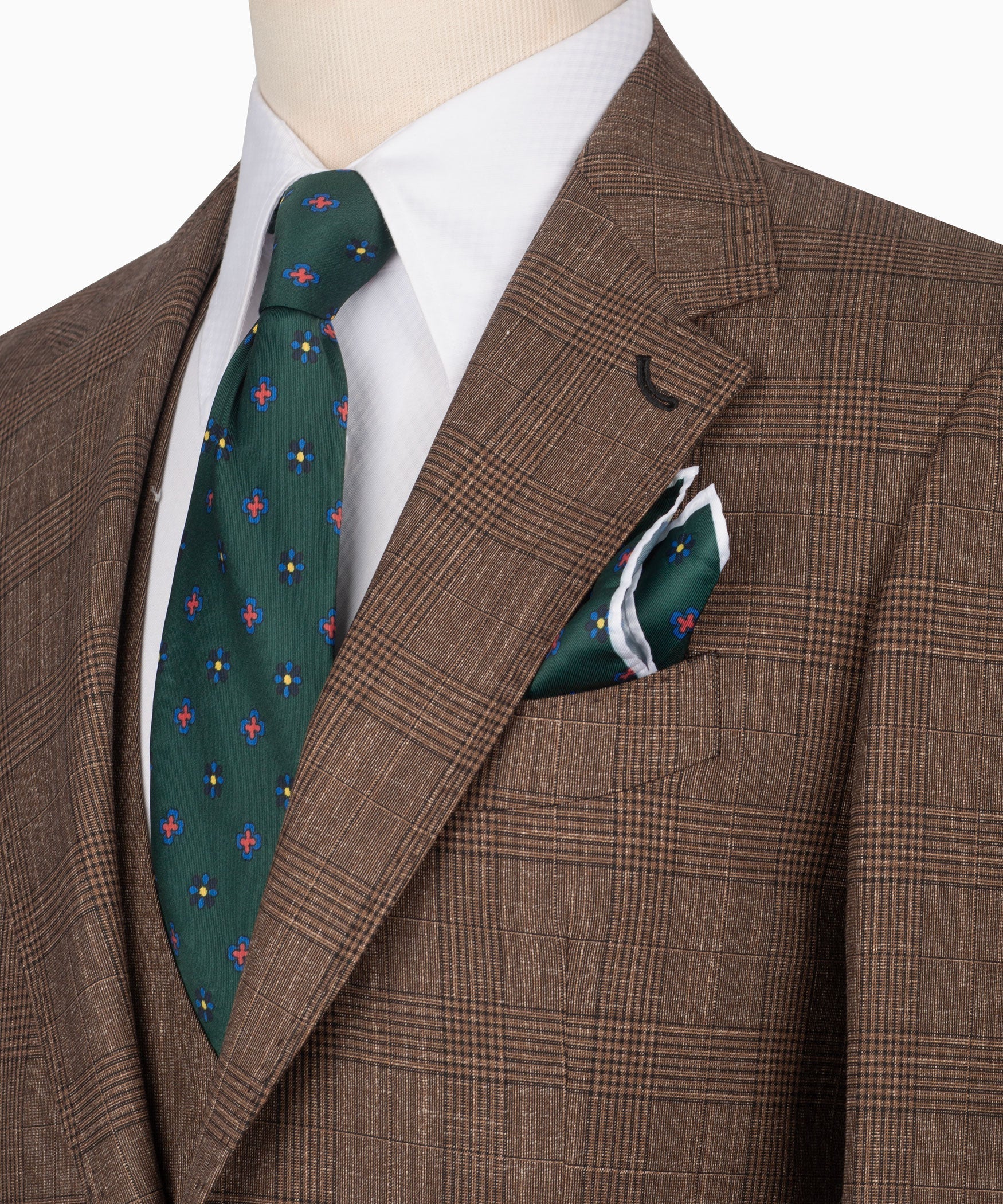 Close-up: brown plaid suit jacket lapel, green patterned tie, and pocket square