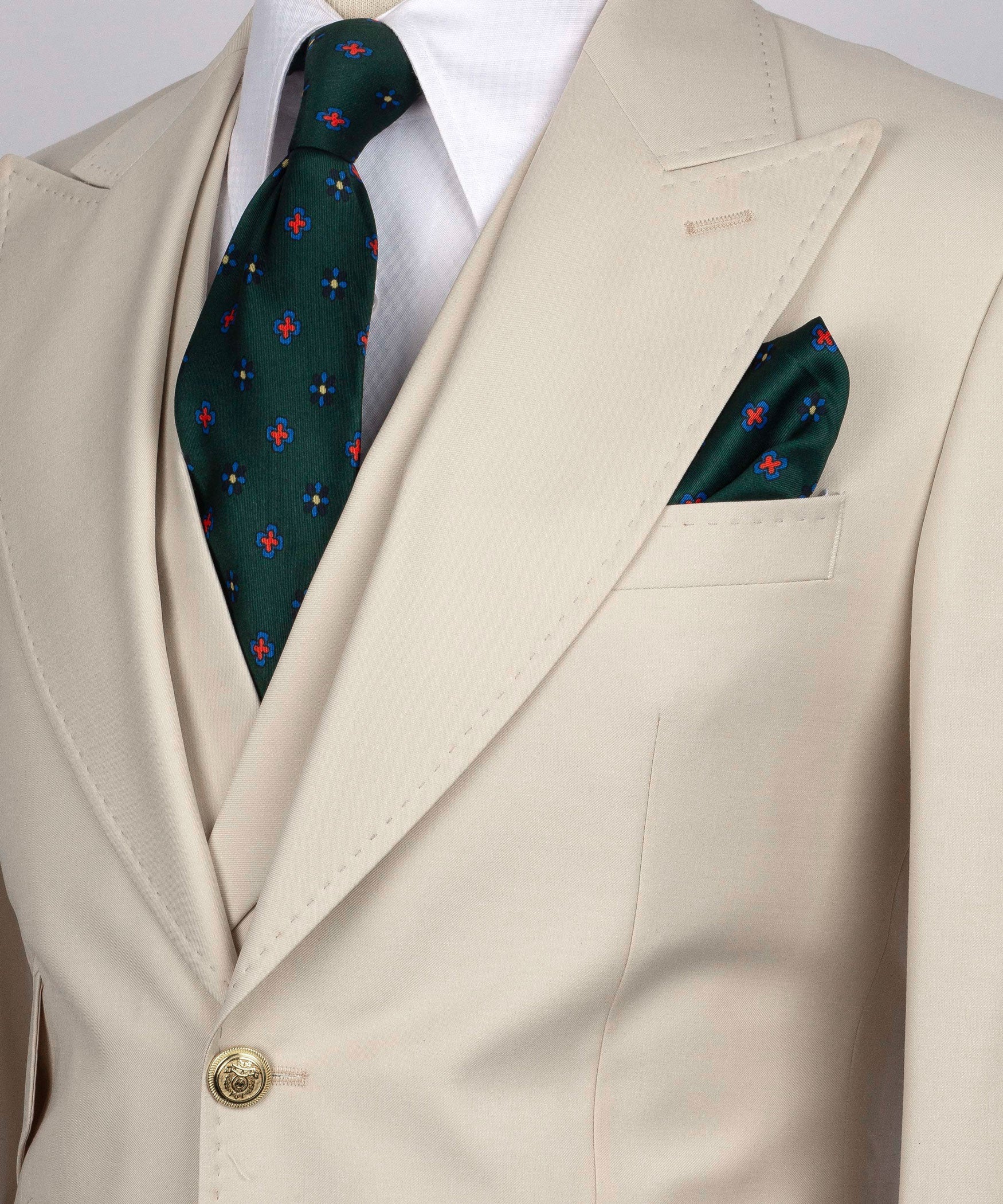 Close-up beige blazer lapel with green patterned tie and folded pocket square