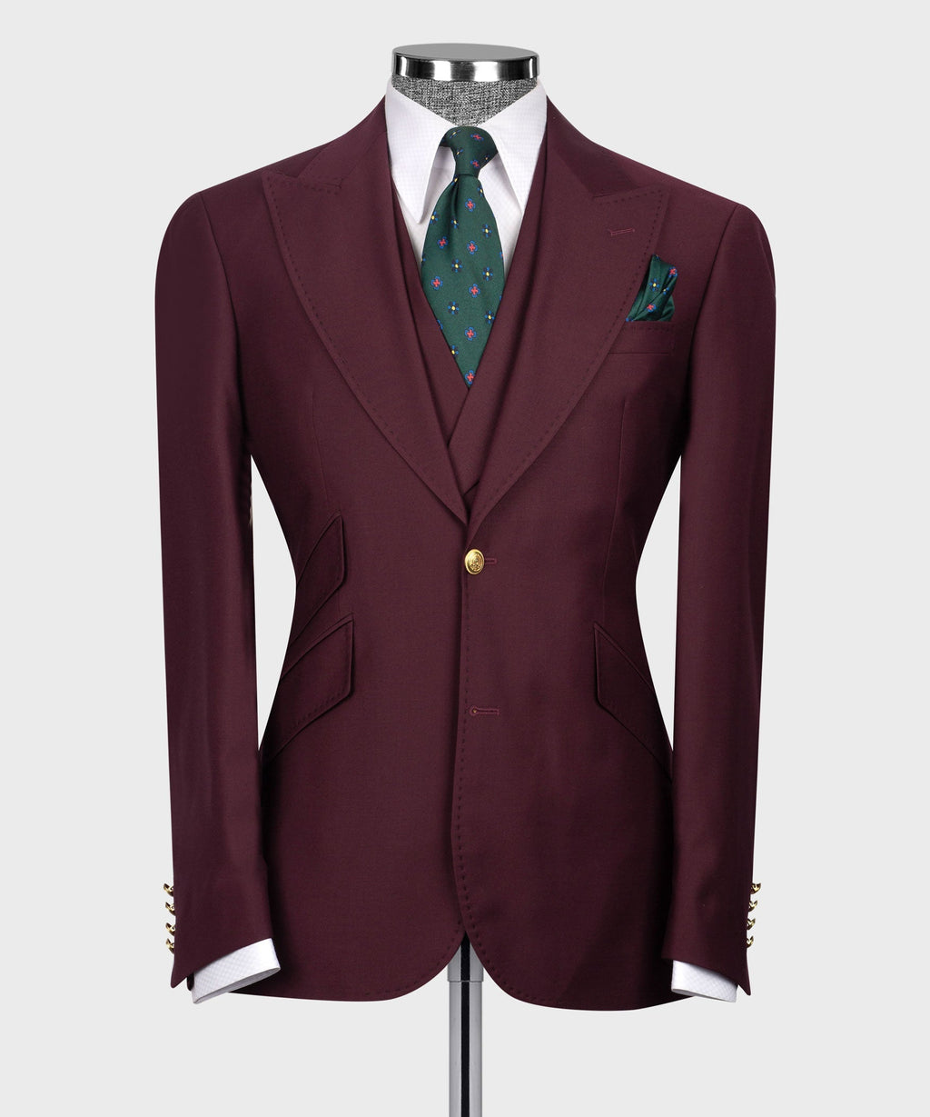 Burgundy suit blazer front with gold button closure, flap pockets, and green patterned tie.