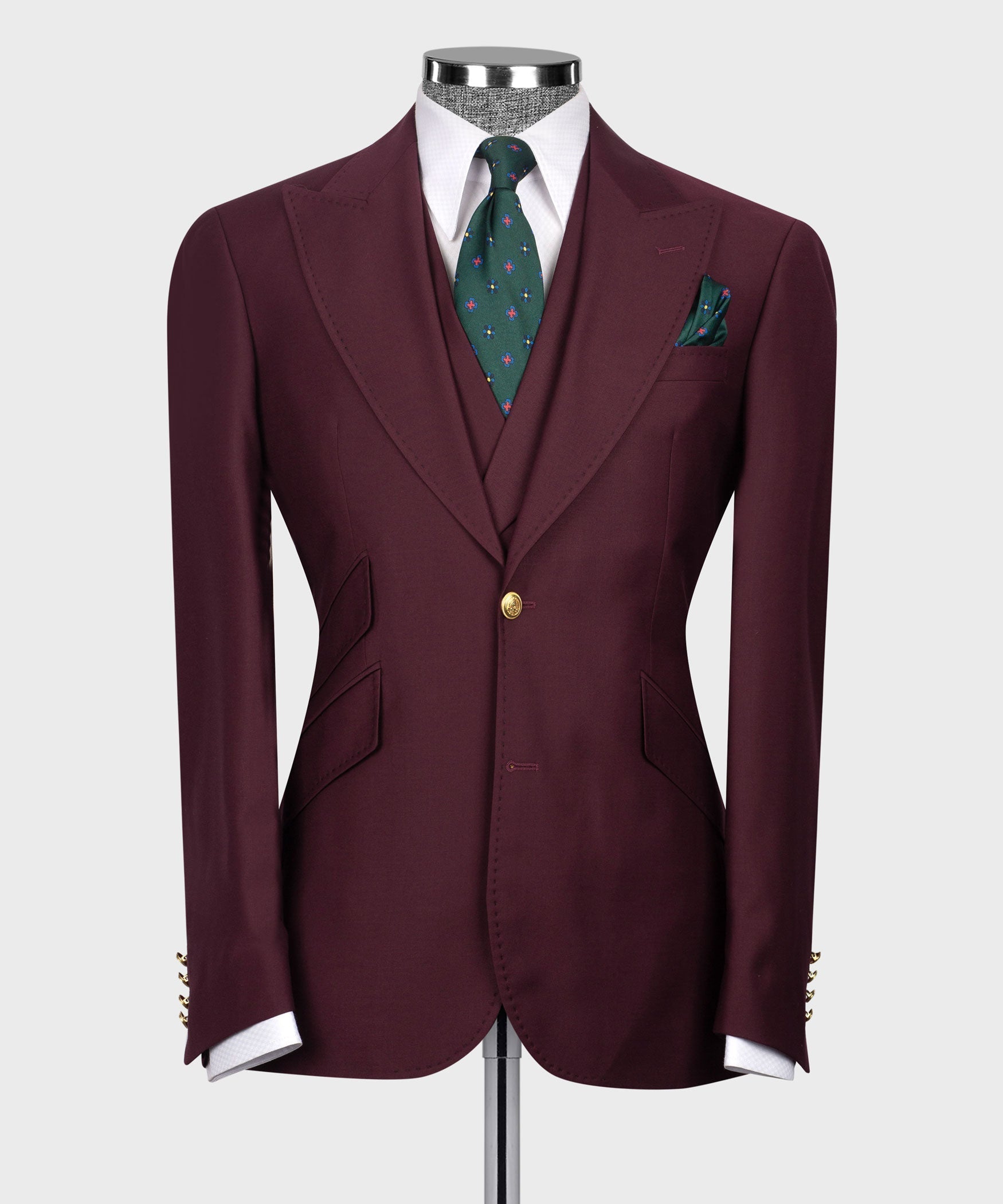 Burgundy suit blazer front with gold button closure, flap pockets, and green patterned tie.