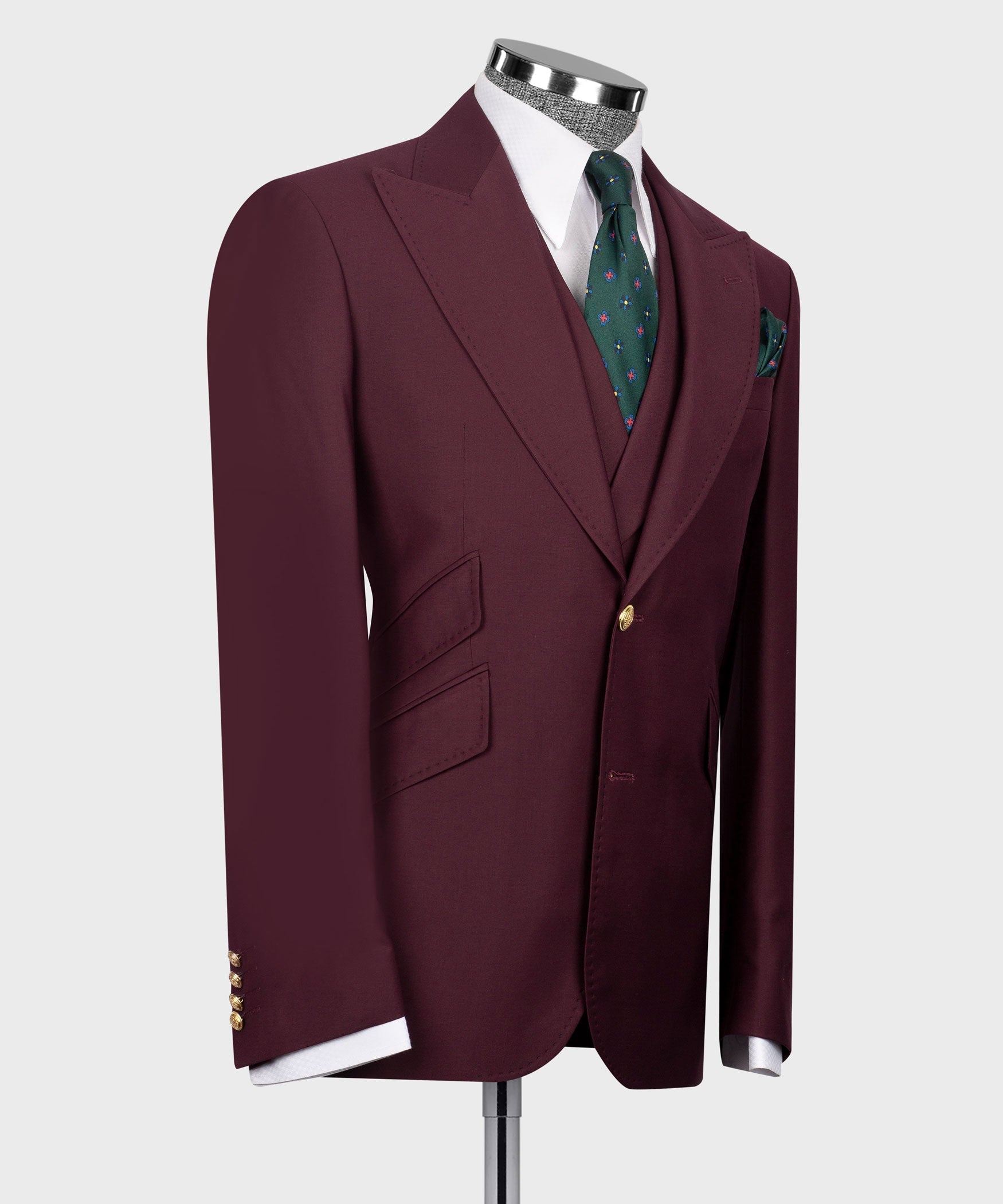 Burgundy suit blazer with notch lapel and gold buttons; green patterned tie and pocket square.