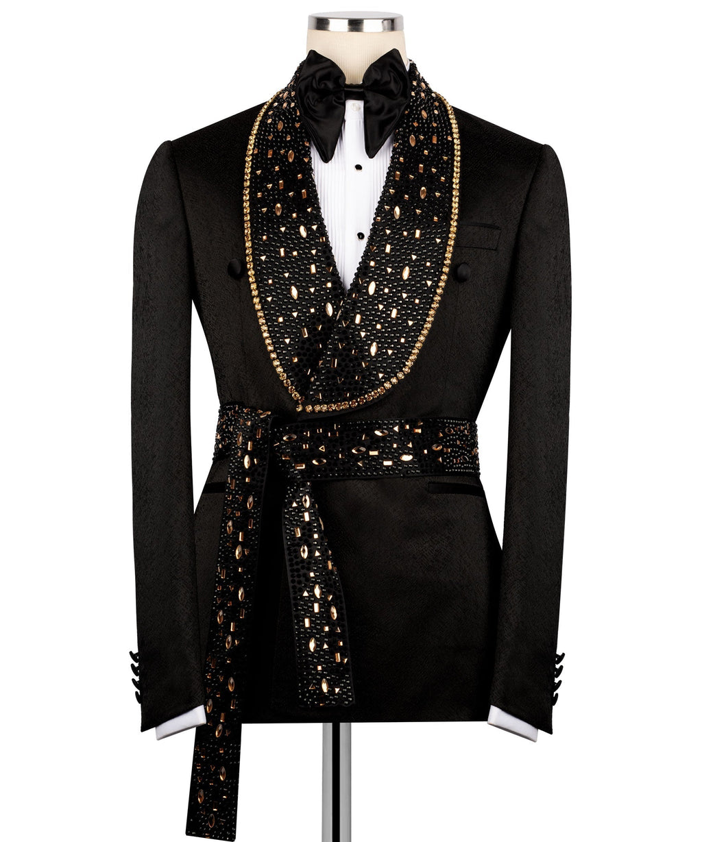 Men's black tuxedo jacket with gold stone embroidery, bow tie, and belted waist detail