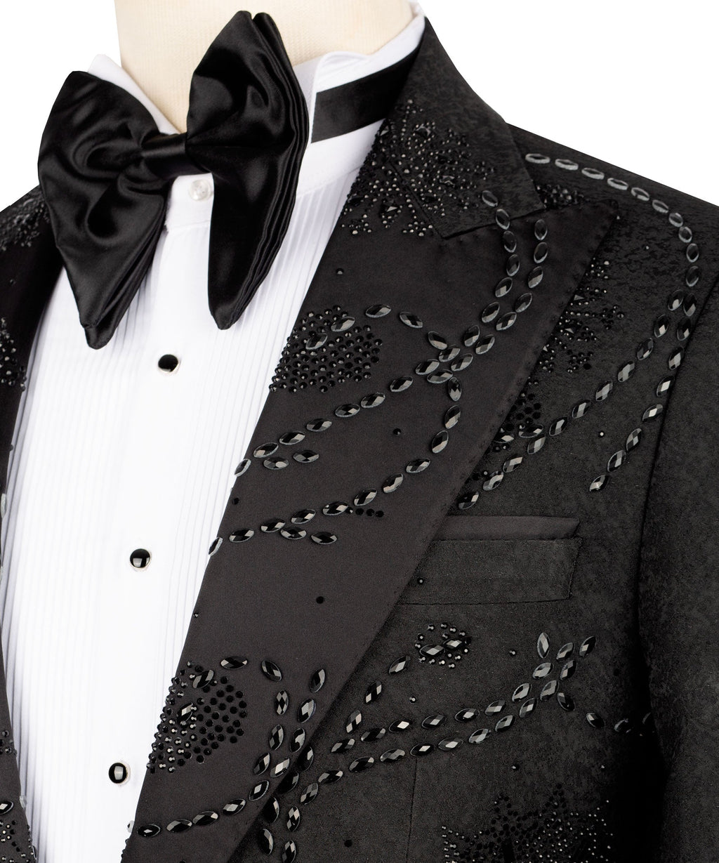 Close-up: black tuxedo lapel with embroidered swirl and oval bead details plus bow tie