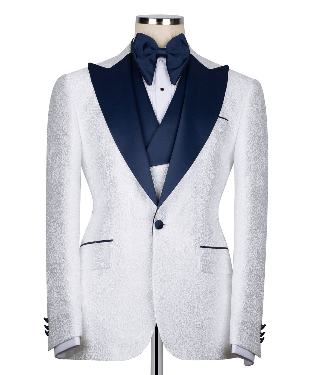 White tuxedo jacket with dark blue V-shaped lapels and single-button closure; tailored fit.