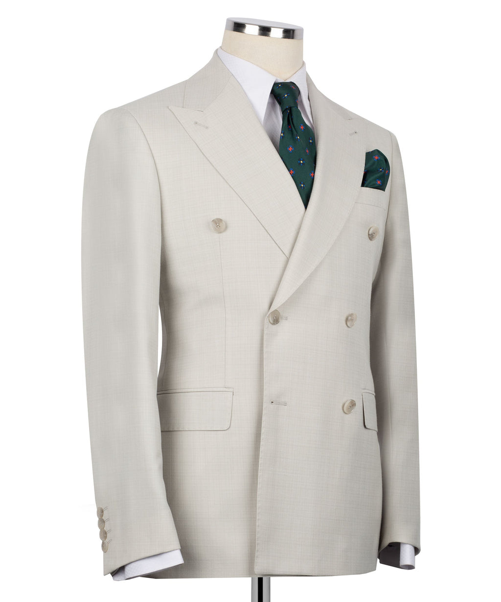 Beige double-breasted suit jacket with green patterned tie and matching pocket square