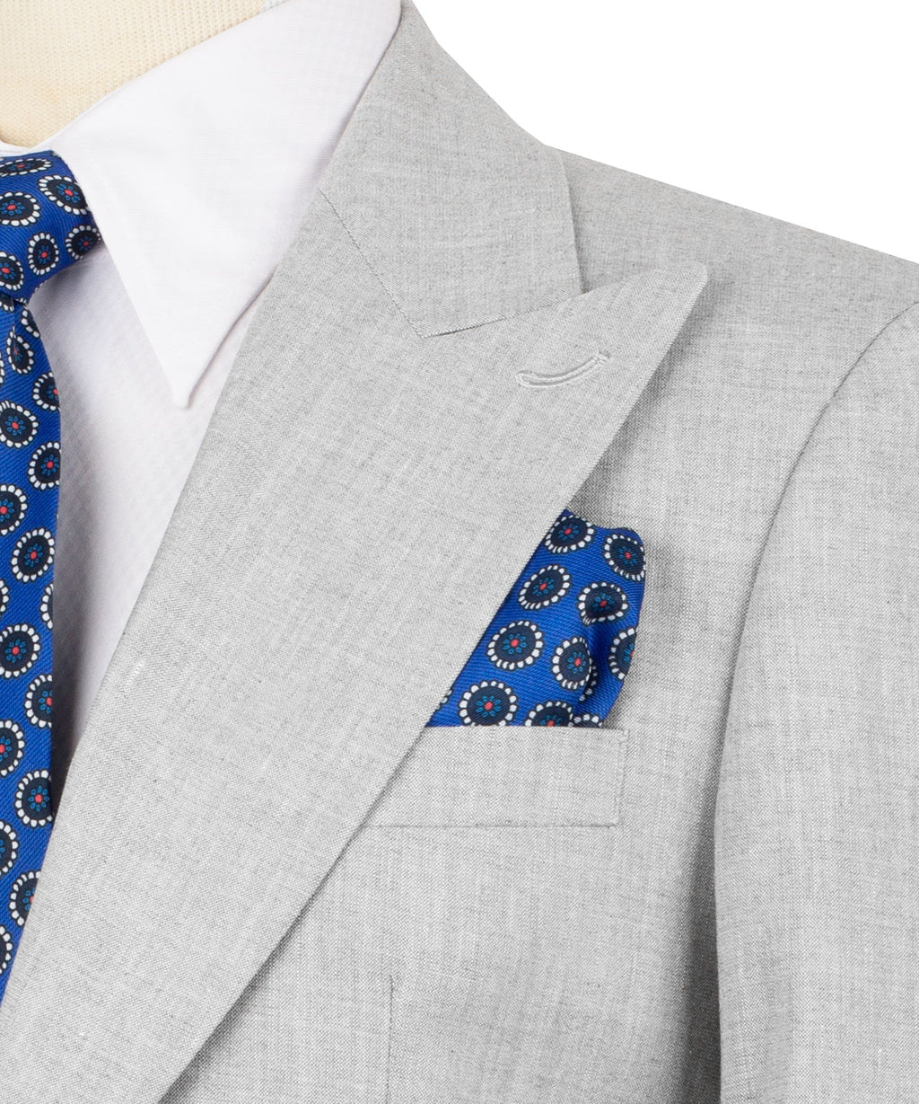 Close-up of light gray linen suit lapel with blue patterned pocket square