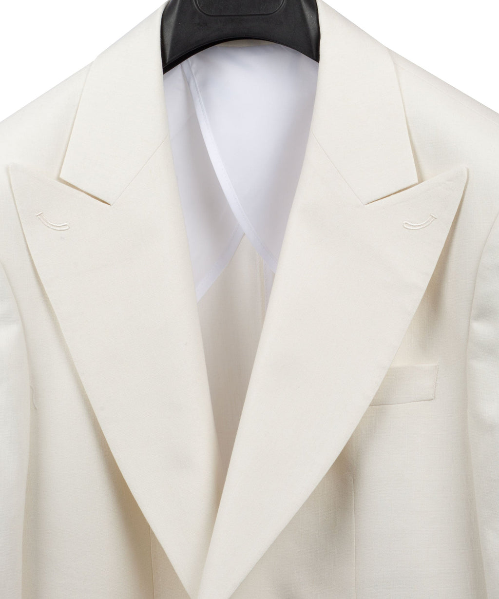 Cream linen blazer close-up of peaked lapels and welt pockets with white shirt collar