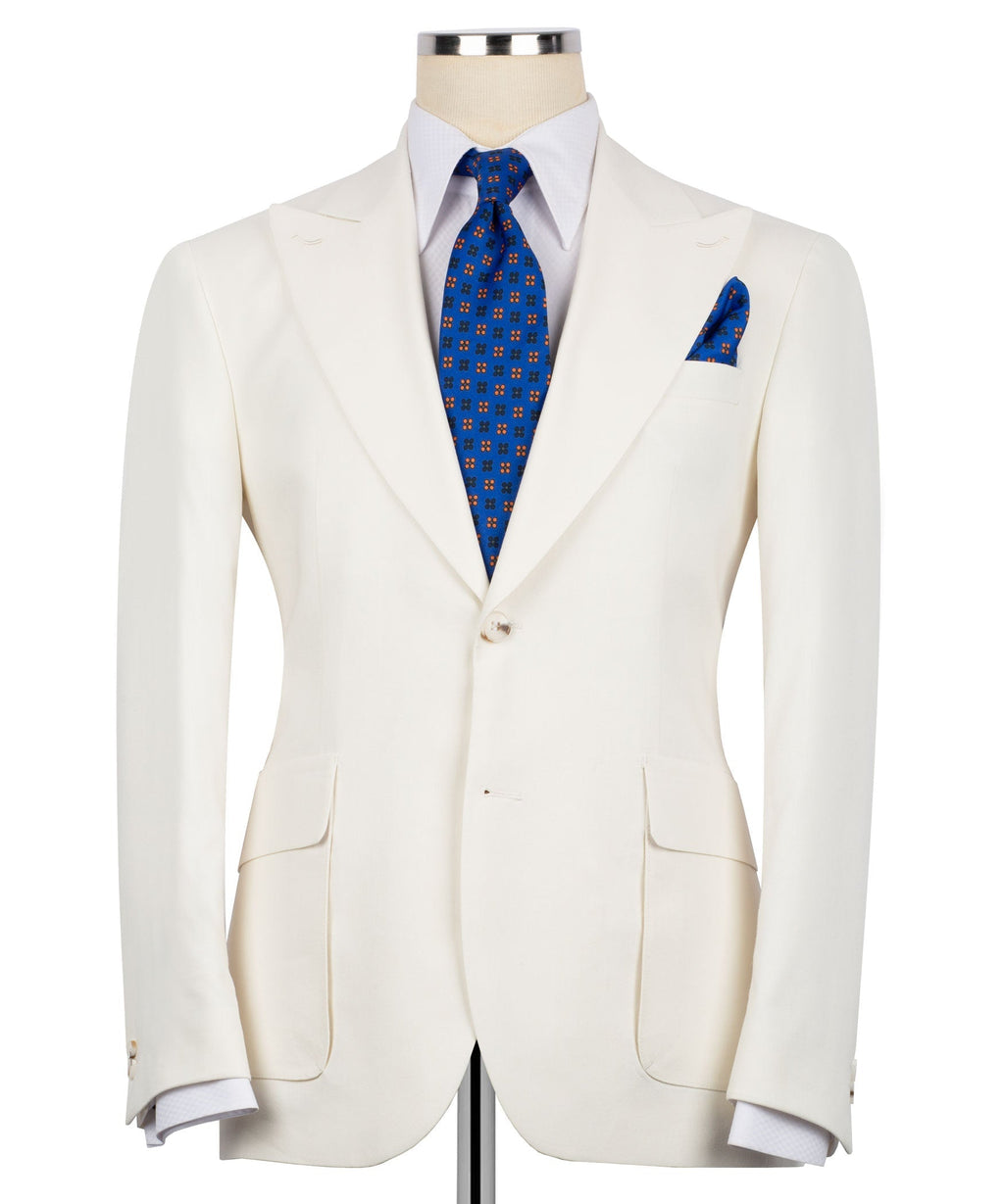 Cream linen blazer with notch lapels, flap pockets, and blue tie + pocket square