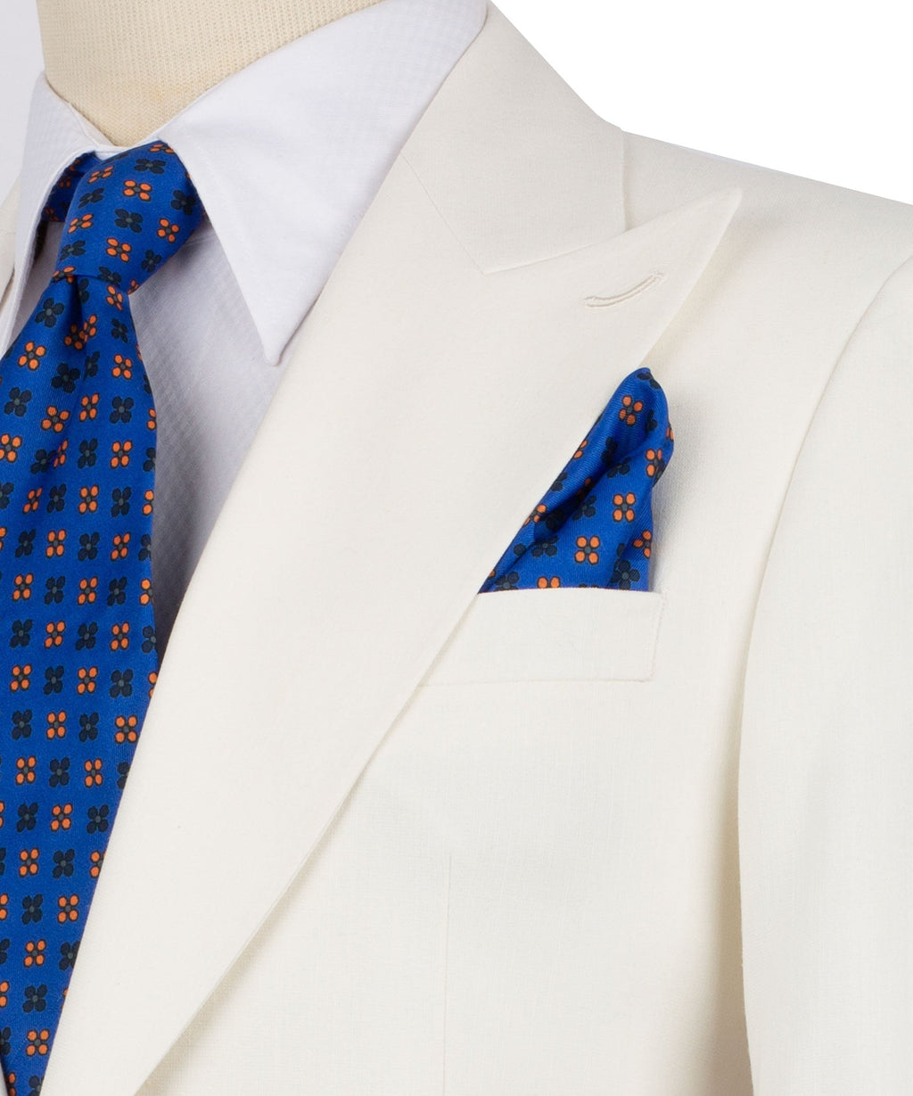 Cream linen blazer detail: blue patterned tie and matching pocket square, close-up lapels