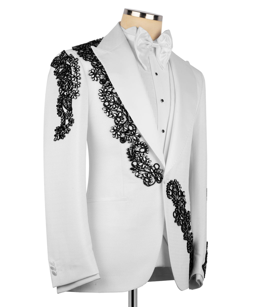 White tuxedo jacket with black stone lace embroidery across shoulder and front panel