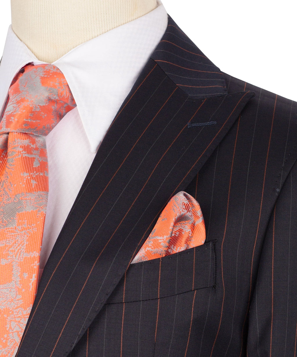 Dark pinstripe blazer close-up with lapel, orange pocket square, and chest welt pocket