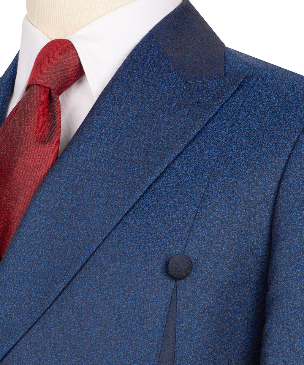 Blue suit lapel and breast pocket detail with textured fabric and red tie knot